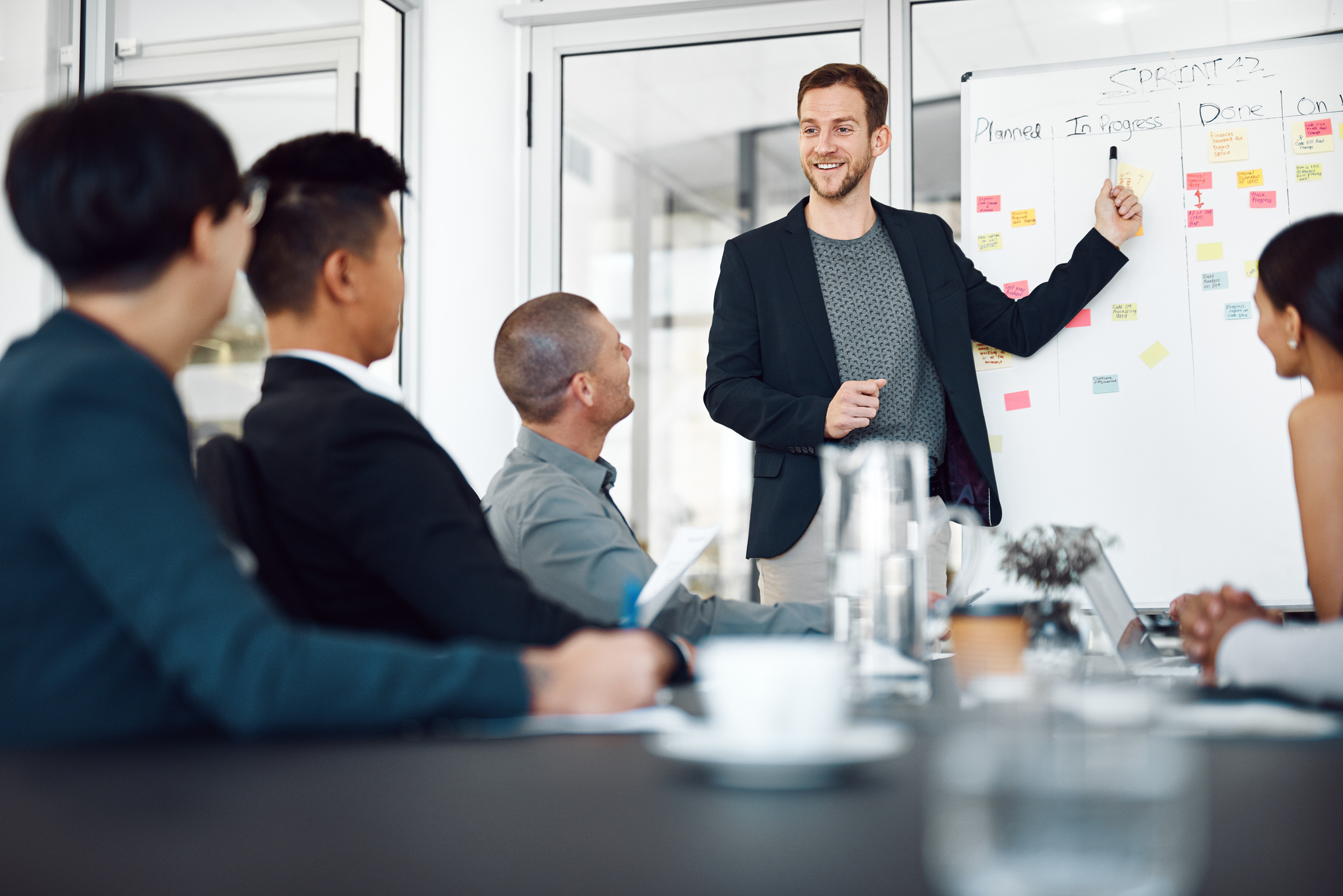 Management Team Meeting with a man pointing to and in front of the board